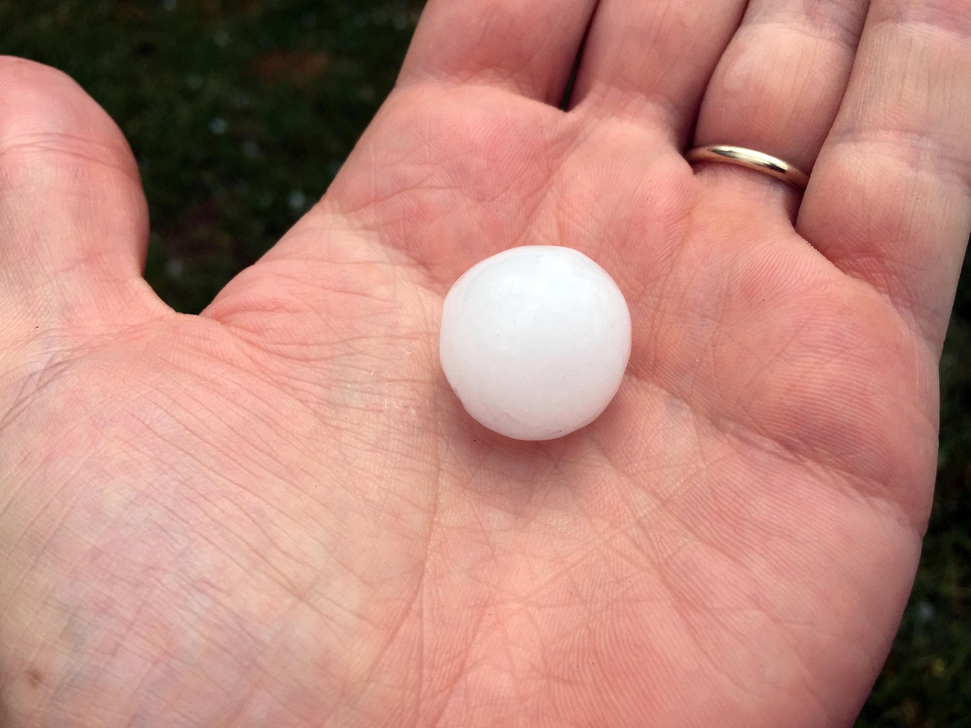 golf ball sized hail stone in a man's palm